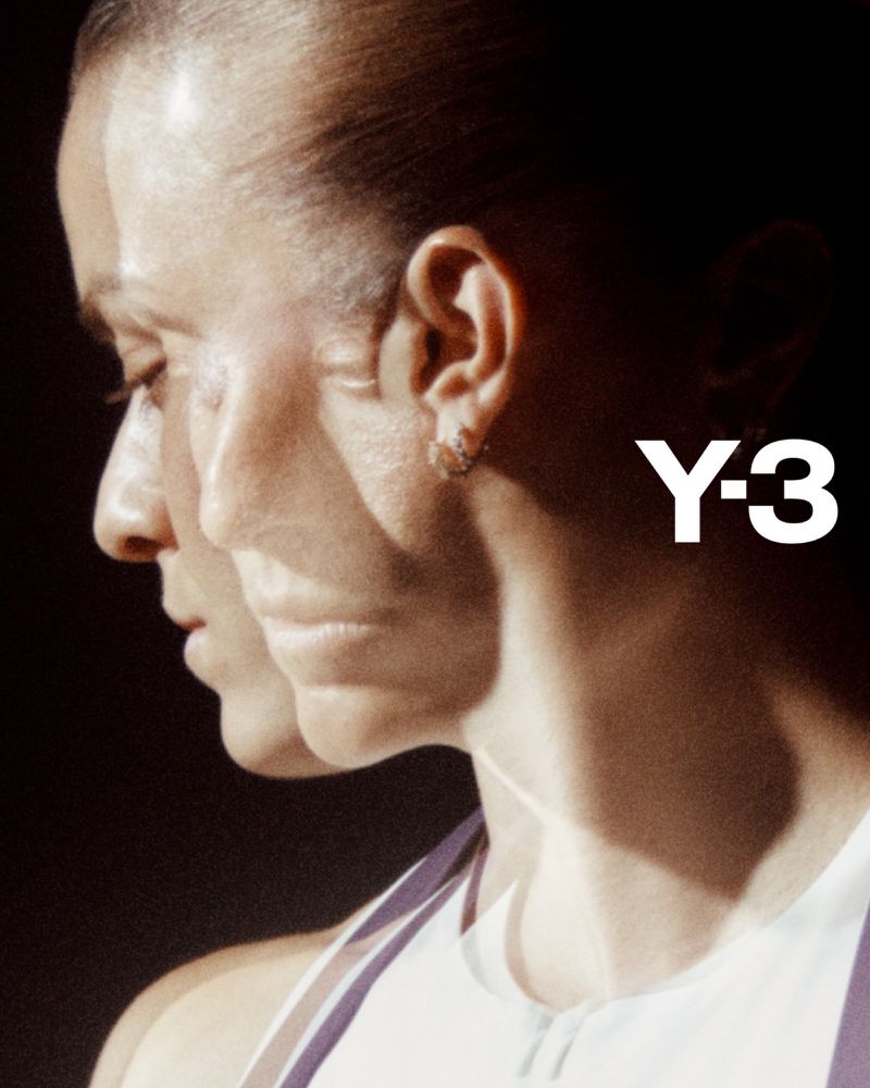 Woman's profile with soft, diffused lighting highlighting skin and the bold Y-3 logo against a dark backdrop, evoking modern style.