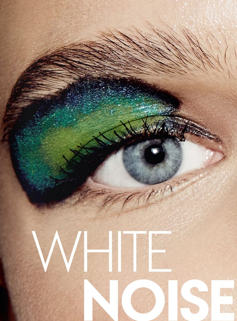 Extreme close-up of a blue eye wearing vibrant green and teal graphic eyeshadow with the text WHITE NOISE across the bottom.