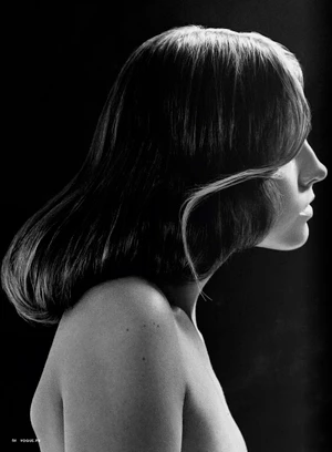 Profile portrait of a woman with dark shoulder-length hair and highlights in dramatic black and white lighting.
