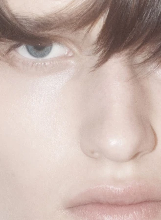 Close-up portrait of a model's face focusing on eye and nose with soft lighting for an editorial beauty story.