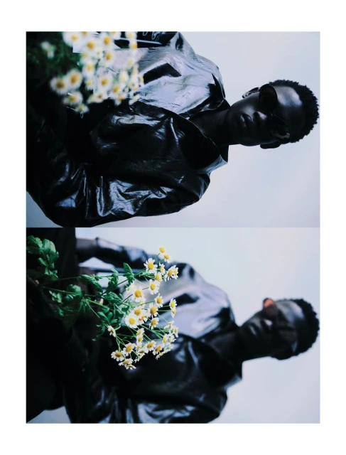 Stylish portrait of a black male model holding a bouquet of daisies in a duplicated vertical image, wearing a glossy jacket and sunglasses.