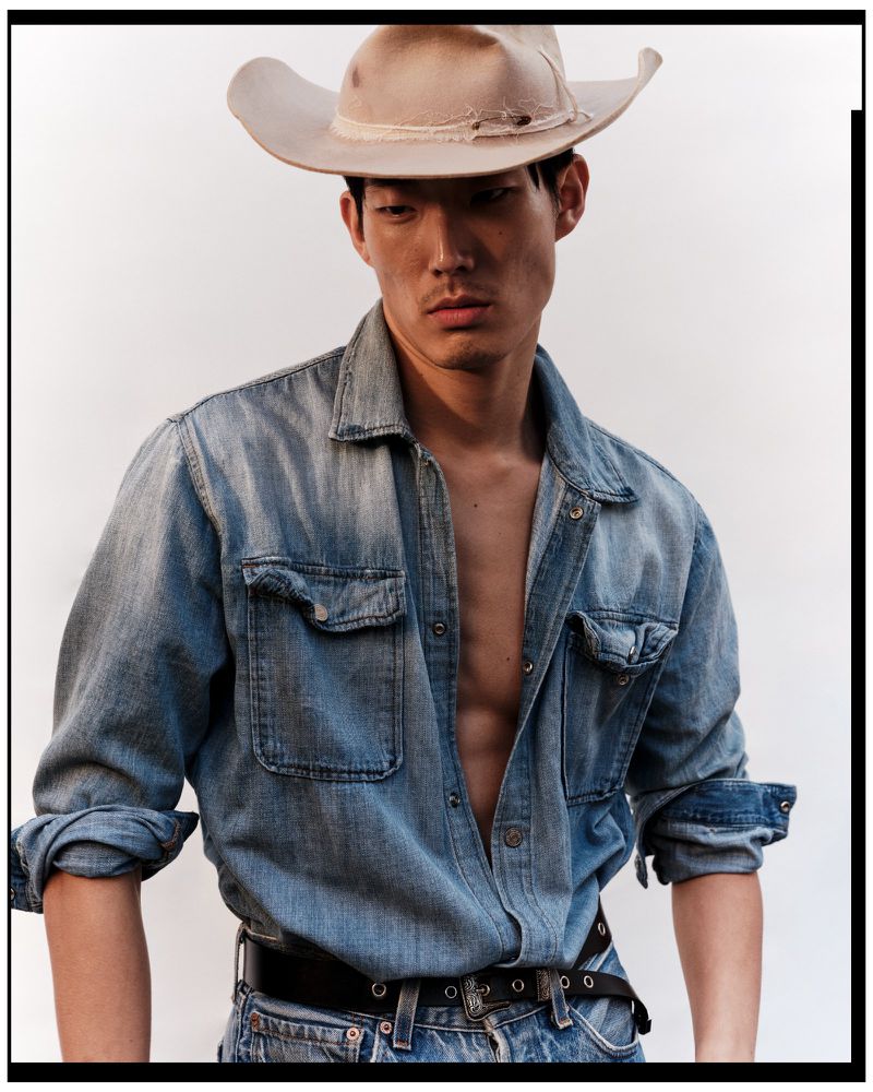 Model Juhyung Kang wearing a beige cowboy hat and an open denim shirt over jeans against a white studio background.