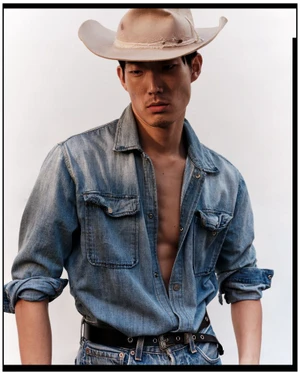 Model Juhyung Kang wearing a beige cowboy hat and an open denim shirt over jeans against a white studio background.