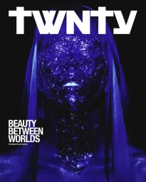 Portrait of a model covered in a textured, dark purple substance against a black background with bold white typography.
