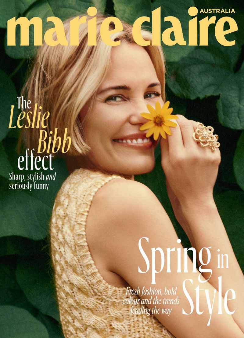 Leslie Bibb smiles holding a yellow flower on Marie Claire Australia cover. Close-up portrait with lush green foliage background.