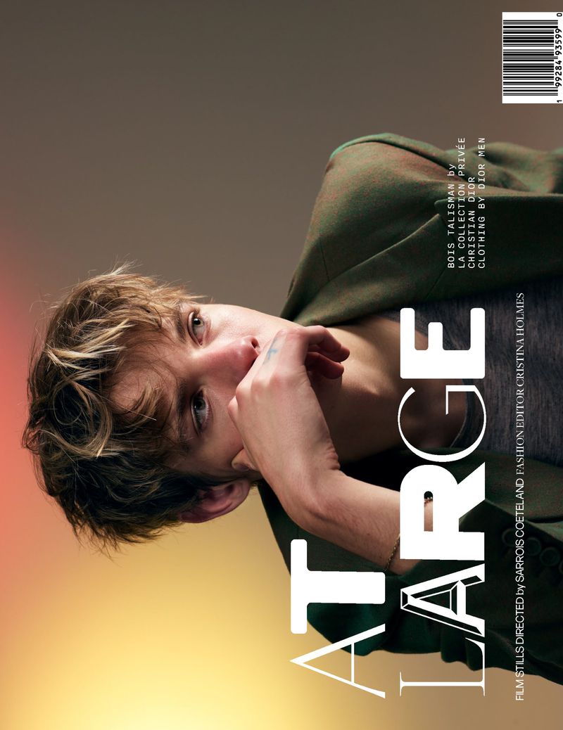 Fashion magazine cover featuring a young adult man in a green jacket, looking at the camera with an intense expression, against a gradient background.