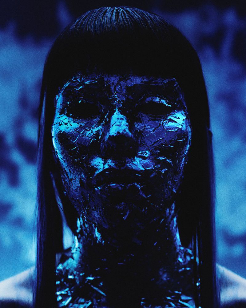 Close-up portrait of a woman with dark hair and face paint, set against a blurred blue background, creating a mysterious and artistic image.