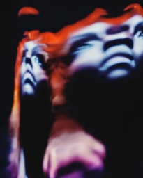 Distorted and blurred photographic portrait of a person with fiery orange light effects against a dark background