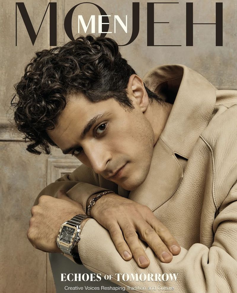 Magazine cover featuring a stylish man with curly hair wearing a tan jacket, a wristwatch, against a neutral backdrop.