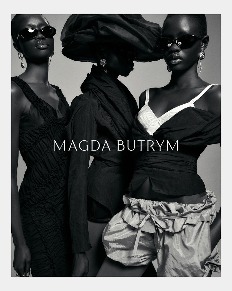 Black and white fashion shot featuring three Black female fashion models wearing dresses, earrings, and sunglasses against a plain backdrop.