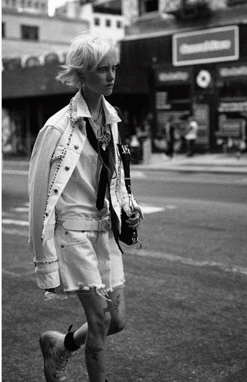Monochrome shot of a stylish young adult female walking in an urban setting wearing a studded denim jacket and distressed denim shorts.