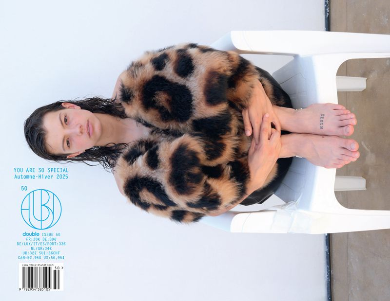 Magazine cover featuring a seated young woman in a patterned fur coat. She's sitting on a white plastic chair with feet exposed.