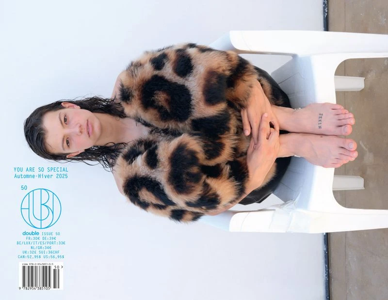 Magazine cover featuring a seated young woman in a patterned fur coat. She's sitting on a white plastic chair with feet exposed.