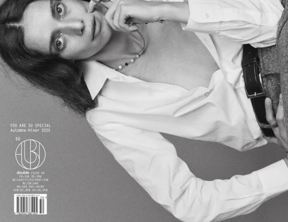 Monochrome fashion editorial portrait of a woman wearing a white shirt against a neutral grey backdrop.