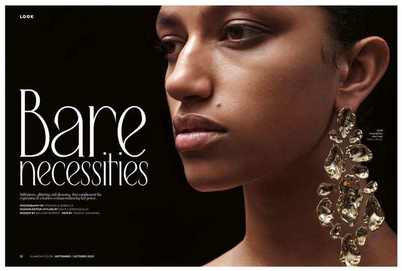 Close-up beauty shot of an adult woman with gold chandelier earrings against a dark background in a magazine editorial spread.