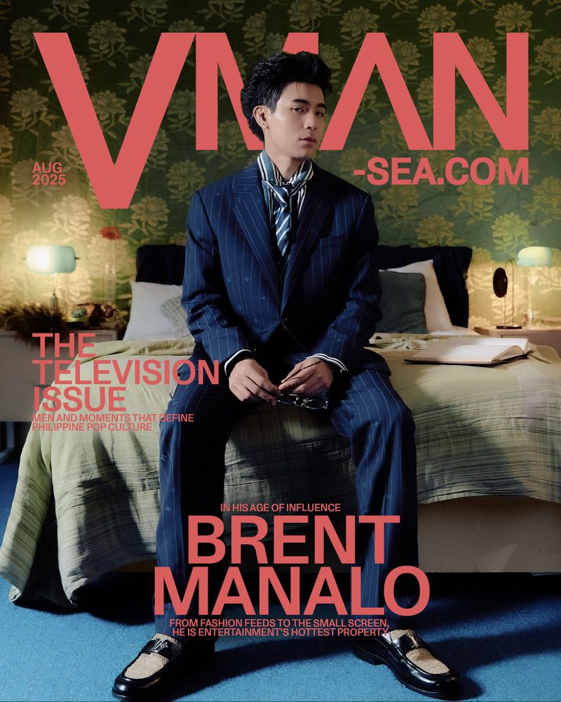 Magazine cover featuring a man in a pinstripe suit sitting on a bed with floral wallpaper, promoting television issue and Brent Manalo.