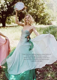 Margot Robbie smiling in a flowing blue and green dress holding a tambourine outdoors for Harper's Bazaar Australia by Max Doyle