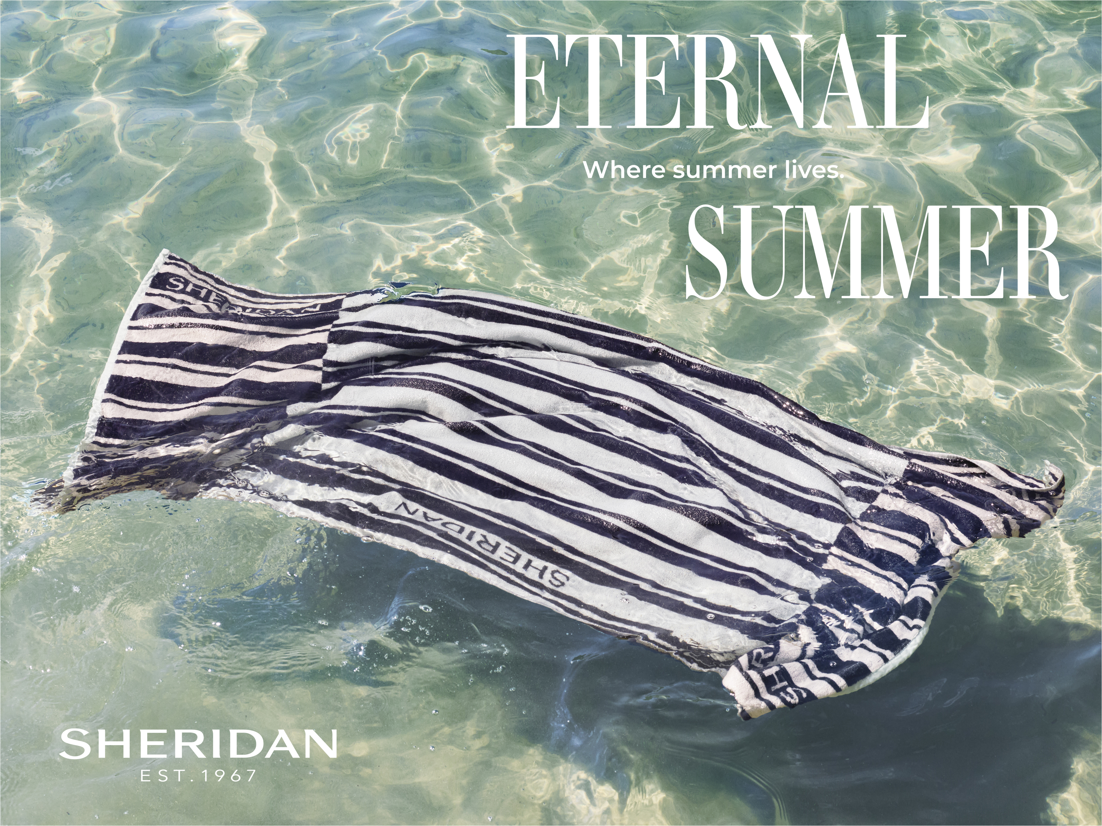 Stripped Sheridan brand towel floating in shallow, clear water on a sunny day, creating an image ideal for travel and fashion industries.