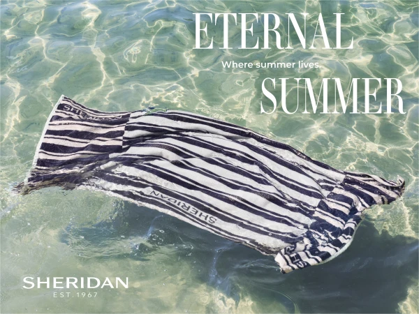 Stripped Sheridan brand towel floating in shallow, clear water on a sunny day, creating an image ideal for travel and fashion industries.