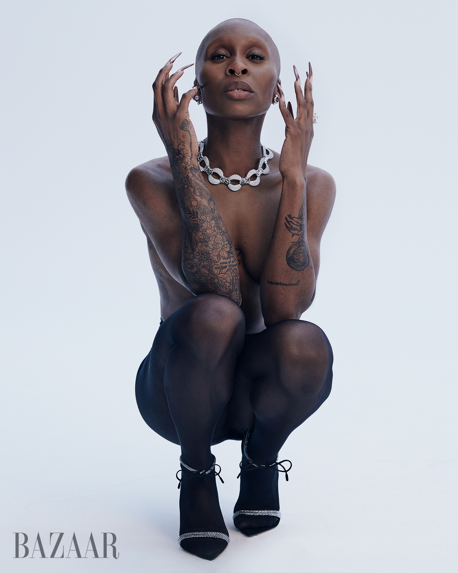 Cynthia Erivo crouching in black tights and statement jewellery against a pale backdrop for a Harper's Bazaar U.S. feature.