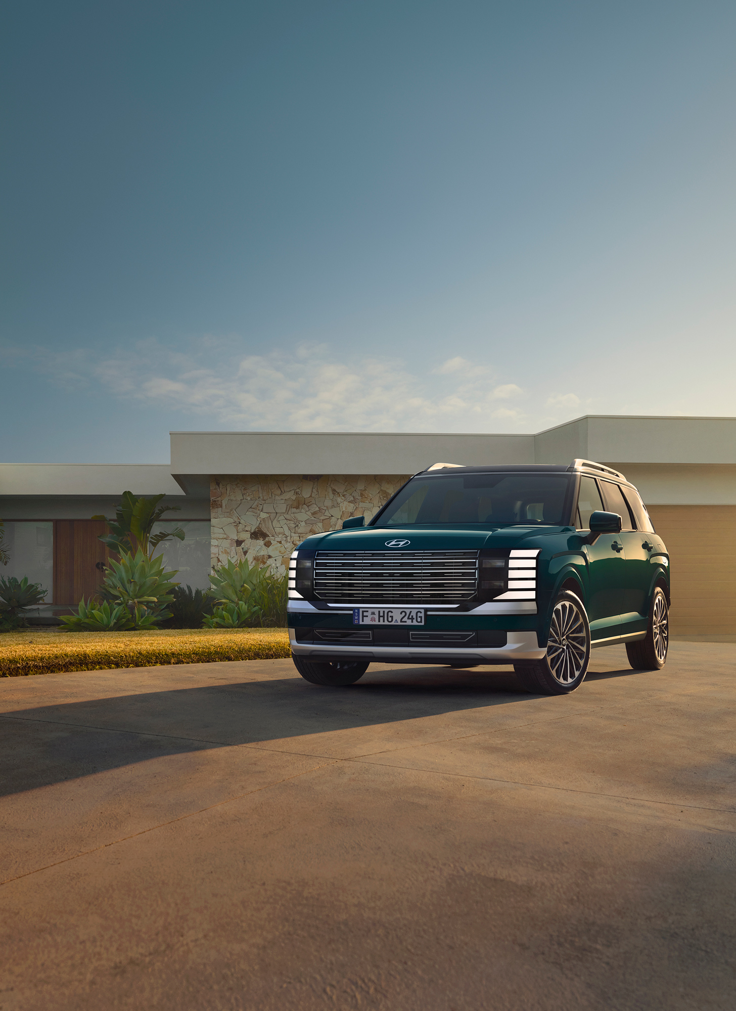 A dark green sport utility vehicle parks outside a modern house with a flat roof on a sunny day in a suburban neighborhood.