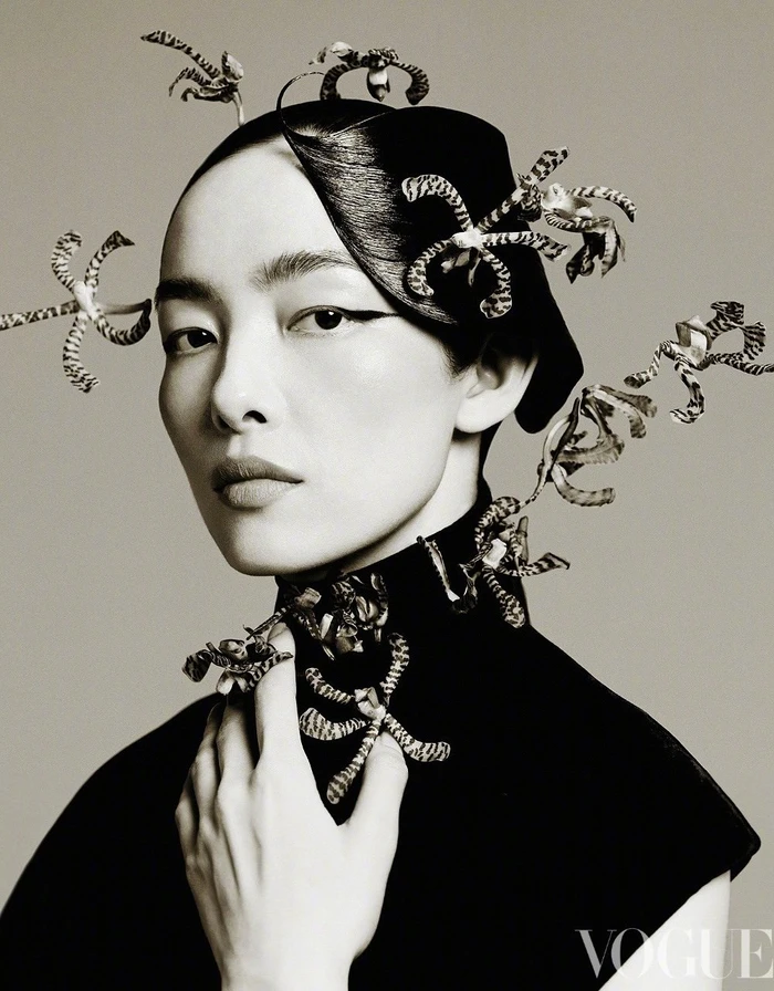 FeiFei Sun posing with patterned orchids woven into her hair and collar in a monochrome Vogue China portrait.