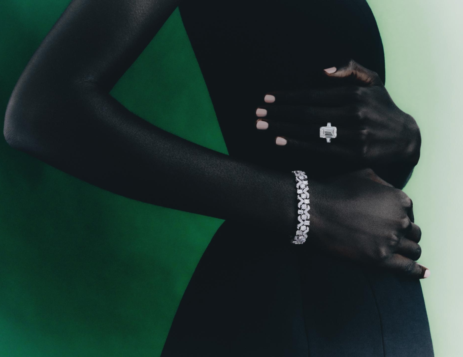 Elegant jewelry fashion shoot featuring an adult woman with diamond bracelet and ring against a green studio backdrop.