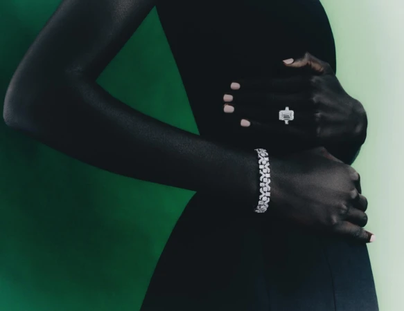 Elegant jewelry fashion shoot featuring an adult woman with diamond bracelet and ring against a green studio backdrop.