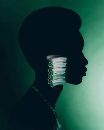 Profile portrait of an adult female silhouetted against a green background, wearing jewelry and a modern hairstyle, studio shot.