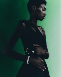 Black woman wearing a dark dress, diamond bracelet, and ring against a gradient green background for Harrods.