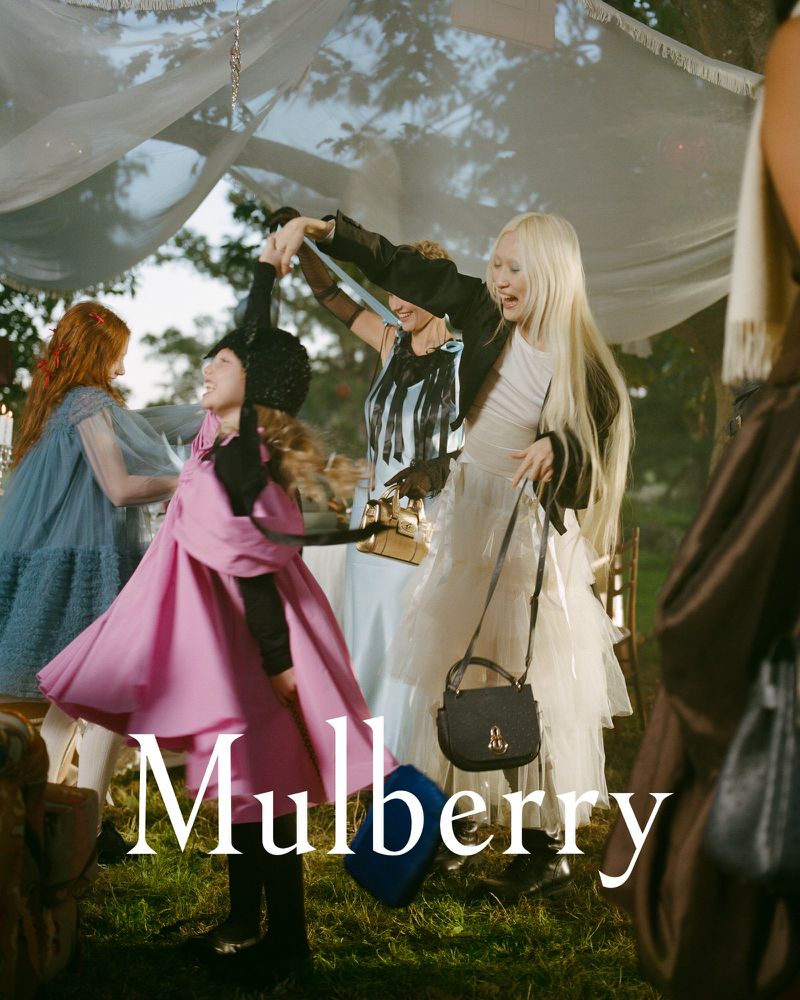 Fashion editorial image of a group of women and a child dancing outside under a decorated canopy, featuring dresses, purses, and text overlay.