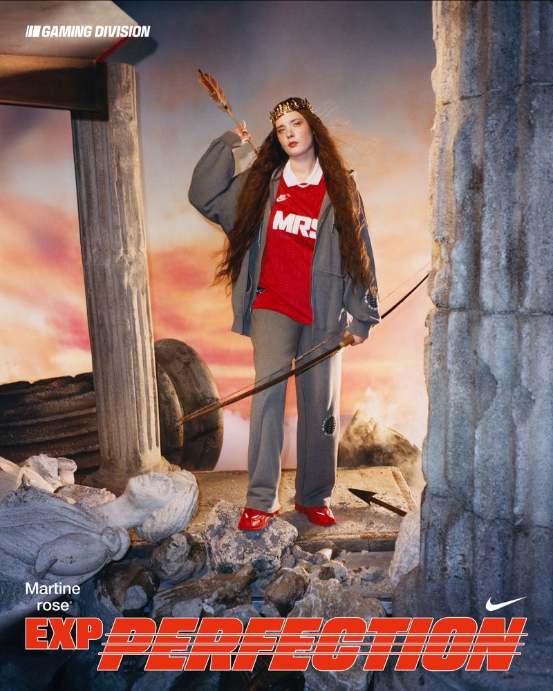Woman in sportswear and crown poses with bow and arrow against a crumbling architectural backdrop, gaming ad for Nike.