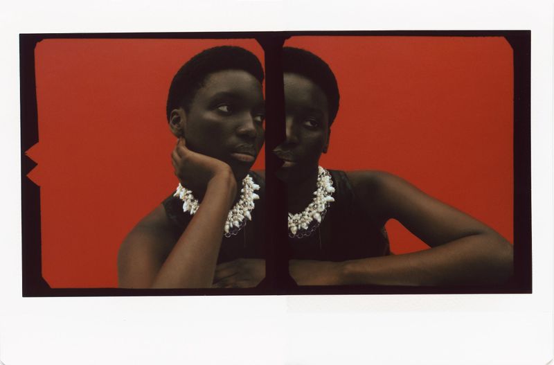 Close-up studio shot of an African-American woman with a pearl necklace, mirrored for a dual image effect, set against a vibrant red backdrop.