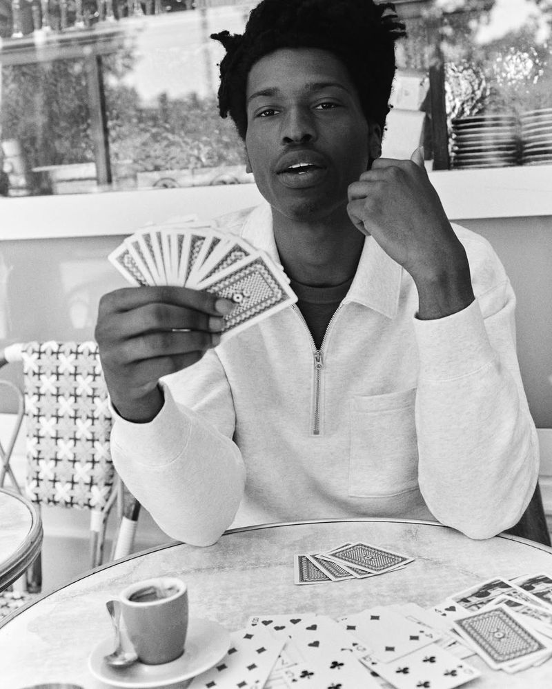 Monochrome shot of a man holding cards at a table with a cup of coffee, creating a vintage aesthetic in an outdoor setting.