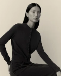 Model wearing a dark button-up cardigan against a neutral studio background for Lisa Yang Fall 2025 Capsule.