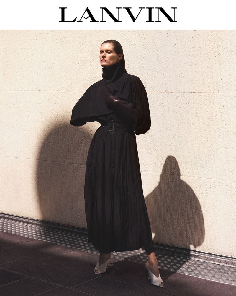 Fashionable woman in long black dress with geometric shadow. Lanvin branded campaign in a warm indoor location.