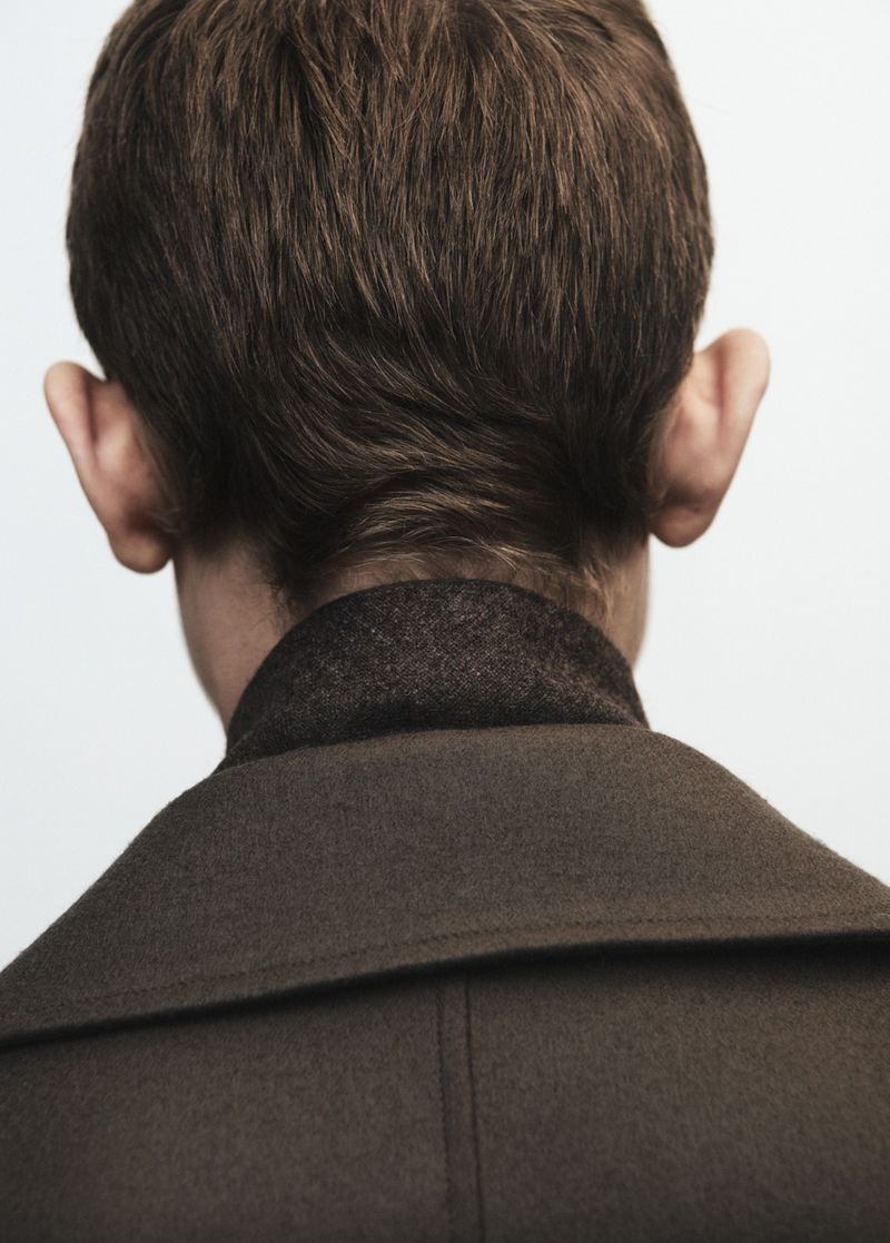 Close-up shot of a light-skinned adult male from the rear, showcasing his brown hair and a dark wool coat against a clean white background.