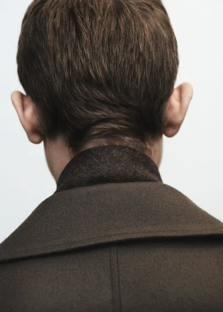 Close-up shot of a light-skinned adult male from the rear, showcasing his brown hair and a dark wool coat against a clean white background.