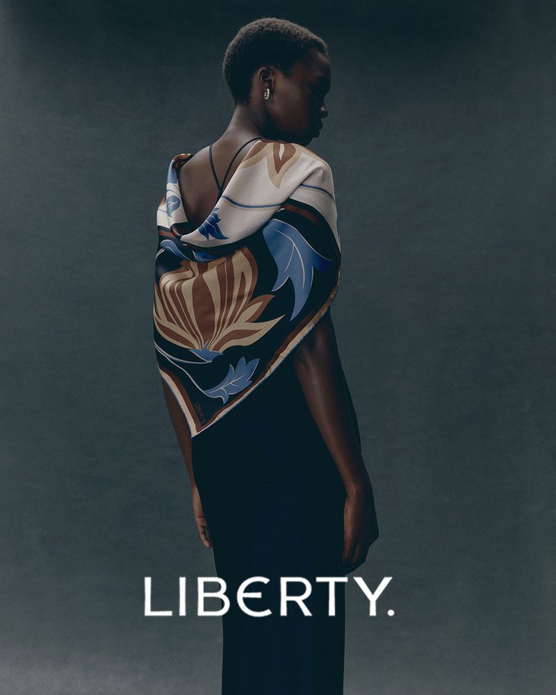 Elegant Black Woman in Fashion Portrait with Patterned Shawl. Woman stands against a muted background showcasing fashion and style.