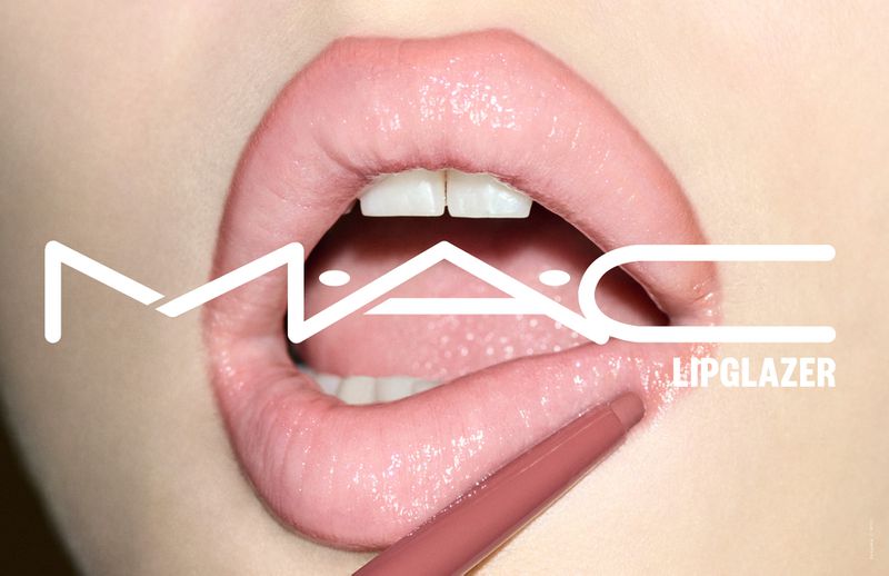 Macro shot of glossy lips being lined with a nude lip pencil, showcasing a close-up of teeth and a MAC Lipglazer logo.