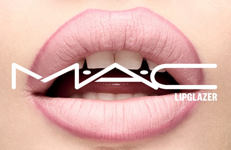 Close-up of a woman's pink-toned lips with teeth slightly visible and the MAC Lipglazer logo overlaying the mouth in white.