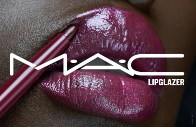 Close-up macro shot of dark glossy plum lips with a lip liner pencil applying product by MAC Cosmetics.