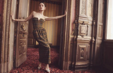Model Vivienne Rohner in a plaid strapless dress leaning in an ornate doorway for Zimmermann Fall RTW, photographed by Benny Horne.