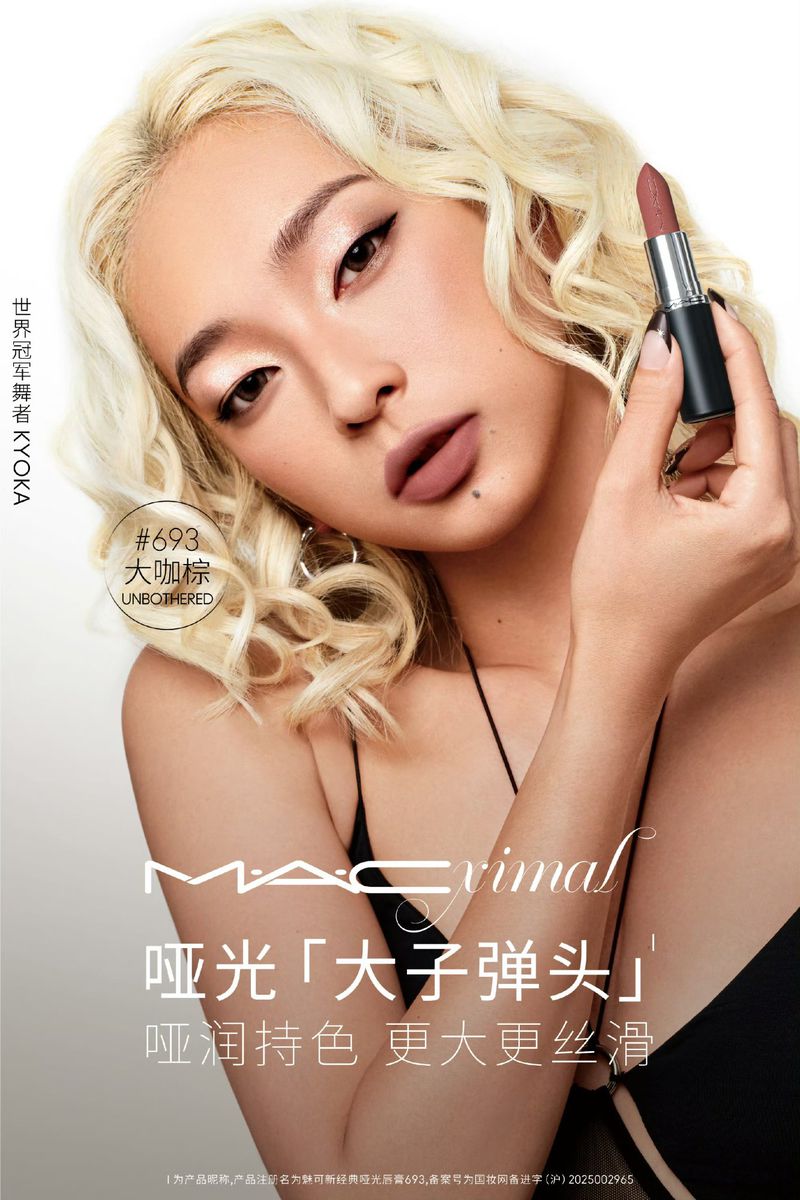 Asian woman with blonde curly hair presents nude lipstick. Beauty shot of lipstick product with model in a light studio setting.