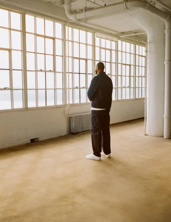 Man standing in an industrial loft with large multi-pane windows looking out into natural light