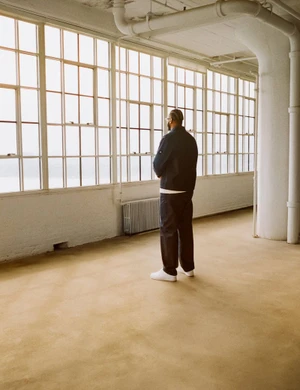Man standing in an industrial loft with large multi-pane windows looking out into natural light