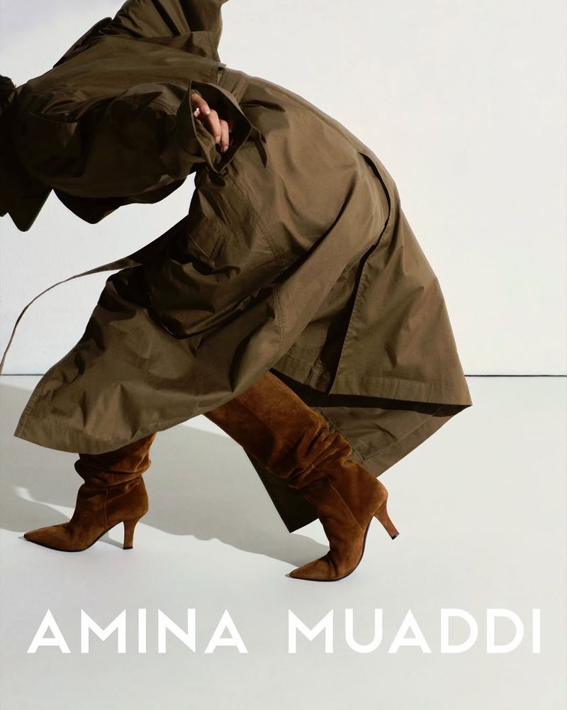 Fashion editorial shot features an adult wearing a brown trench coat and brown suede heeled boots, posing against a neutral background.