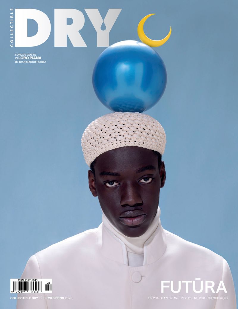 Magazine cover featuring a Black male model wearing a white outfit and a crocheted hat balancing a blue balloon and crescent.