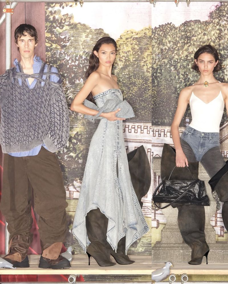 Three fashion models showcase modern apparel in a studio with a scenic backdrop, presenting a blend of casual and high-fashion elements.
