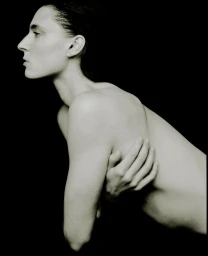 Profile portrait of a model with dark hair in a pose against a solid black background for the AUNU Beauty Campaign